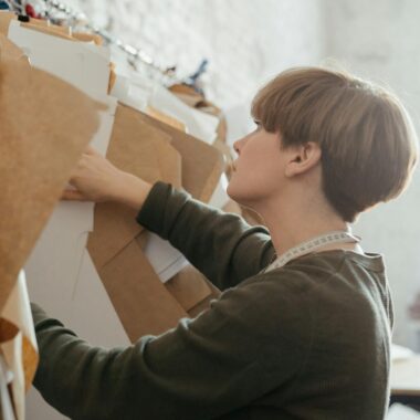 A designer arranges paper patterns in a sewing studio, highlighting creativity and organization.